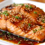 Filets de saumon frais en train de mariner dans une sauce maison au miel, sauce soja, ail et herbes fraîches, prêts à cuire
